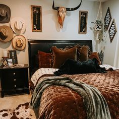 a bed with brown and black comforter in a bedroom next to a cow skull