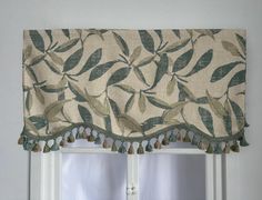 a window with a green leafed valance and tassels on the bottom