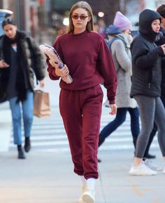 a woman walking down the street in a maroon outfit