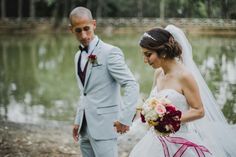 a bride and groom holding hands by the water