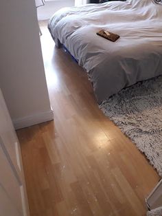 a bed sitting on top of a hard wood floor next to a window in a bedroom