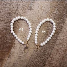 two bracelets with pearls on them sitting on top of a wooden table next to each other