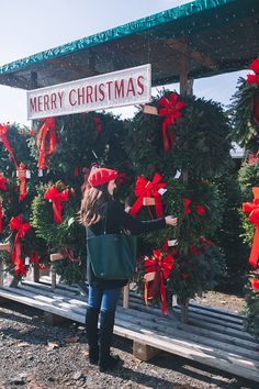 a woman standing in front of a christmas tree with red bows on it's head