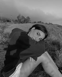 a woman sitting on the ground with her head resting on her hands, in black and white