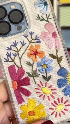 someone is holding up their phone case with flowers on it and buttons in the back