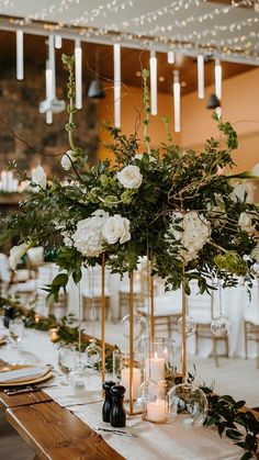 a table with candles, flowers and greenery in vases on top of it