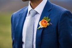 a man in a blue suit with a boutonniere on his lapel