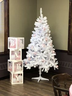 a small white christmas tree sitting next to a baby block set on top of a hard wood floor