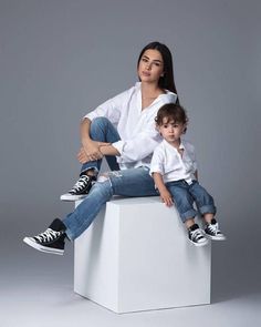 a woman and child sitting on top of a white block