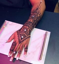 a woman's hand with henna tattoos on her left arm and the other hand