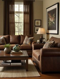 a living room filled with brown furniture and pillows on top of a rug next to a window