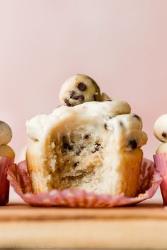 a cupcake with white frosting and chocolate chip toppings is cut in half