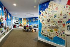 a large mural in the hallway of a children's playroom with tables and chairs