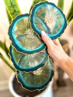 a hand holding a blue and green plate with flowers in the center on top of it