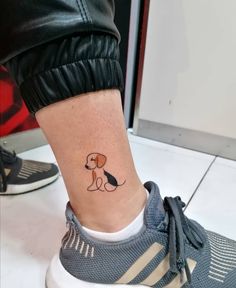 a small dog tattoo on the side of a woman's ankle, with a black and white outline