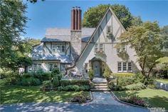 a large white house with lots of trees and bushes around it's front entrance