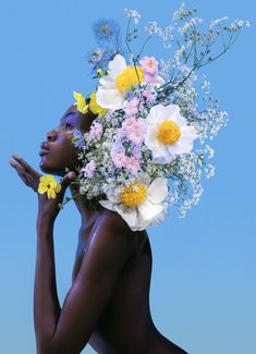 a woman with flowers on her head is posing for the camera in front of a blue sky