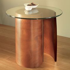 a glass and wood table with a bowl on it's top sitting on a hard wood floor