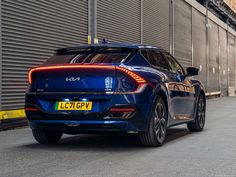 the rear end of a blue car parked in front of a building with shutters