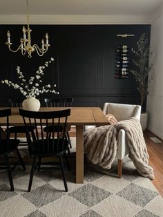 a dining room table with chairs and a rug in front of it, next to a chandelier