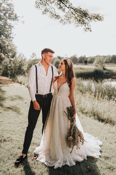 a bride and groom standing together in the grass