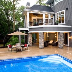 a house with a swimming pool in front of it and an outdoor dining area next to the pool