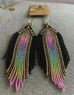 two pairs of black and pink beaded earrings on top of a gray table next to a pair of scissors