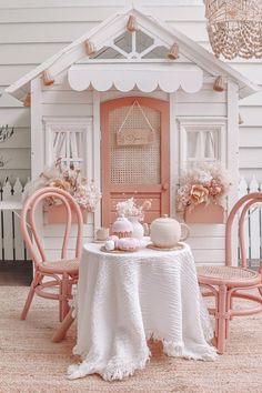 a doll house with two chairs and a table in front of it, set up for a tea party