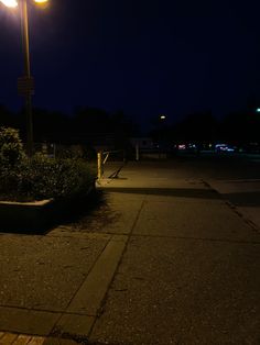 a street light sitting on the side of a road next to some bushes and trees