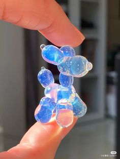 a hand is holding some clear bubbles in the shape of a teddy bear on it's finger