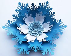 a blue and white paper snowflake on a white surface with the center cut out