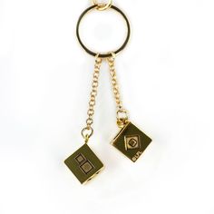 a gold keychain with two square shaped objects hanging from it's sides