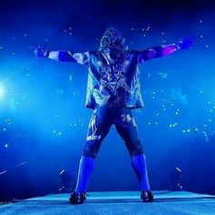 a man standing on top of a stage holding his arms out