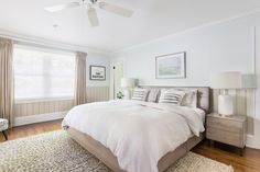 a large white bed sitting in a bedroom next to a window