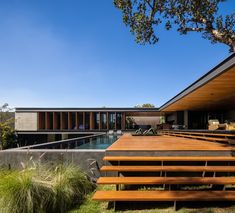 a wooden deck next to a swimming pool in the middle of a lush green field