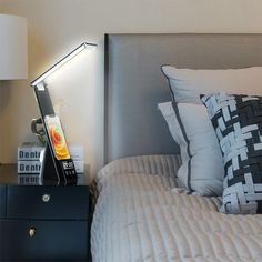 a bed that has some pillows on it and a lamp in the corner next to it