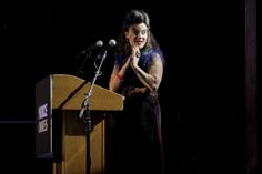 a woman standing at a podium in front of a microphone