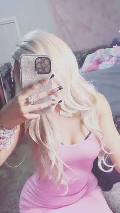 a woman with long blonde hair is holding up her cell phone to take a selfie