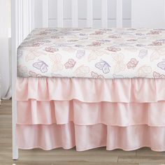 a white crib with a pink bed skirt and matching comforter on the bottom