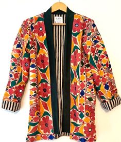 This jacket is part of our new Specialty Collection which redefines handcrafted artisan fashion. Each piece requires extensive labor. This piece required 1-2 months to finish embroidery by women of Banjara Tribe. Specialty Collection: Refined hand fully embroidered stroller length jacket which is fully reversible. Traditional box cut with 2 deep front pockets. Designer finishes and piping. The front placket is wide, full length of the jacket with suede material. Reverse print is a smart, classic stripe which is well suited for office, lunch, etc. Jacket is tailored and designed to be worn open. Stunning blend of colors; avocado, pink, orange, navy. Incredible value based two varied coats in one with exceptional quality. This jacket is cut as a traditional unstructured blazer, considered a Finish Embroidery, Unstructured Blazer, Artisan Fashion, Office Lunch, Types Of Embroidery, Embroidered Shorts, Suede Material, Boho Look, 2 Months