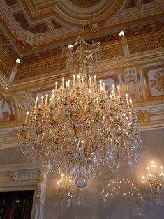 a chandelier hanging from the ceiling in a room with gold and white walls