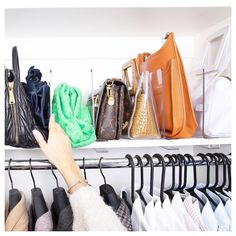 a woman's hand reaching for purses on a rack