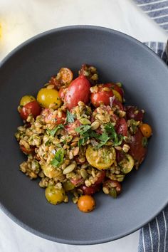 a bowl filled with rice and tomatoes on top of a white table next to a fork