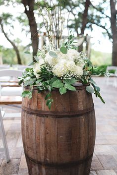 a wooden barrel with flowers and greenery on it