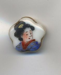 a white and blue glass brooch with a woman's face on it