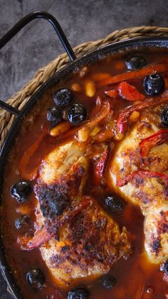 a pan filled with chicken and blueberries on top of a table