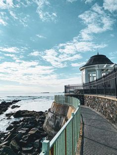 there is a lighthouse on the side of the water by the rocks and fenced in area