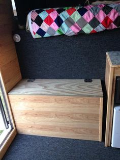 the inside of a small camper with a bed and storage space on the floor