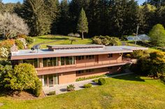 an aerial view of a house in the middle of trees and grass with lots of windows