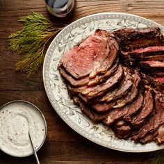 sliced steak on a plate with sour cream and rosemary sprigs next to it